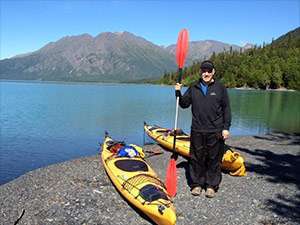 Pancreatic cancer survivor with kayaks by a lake