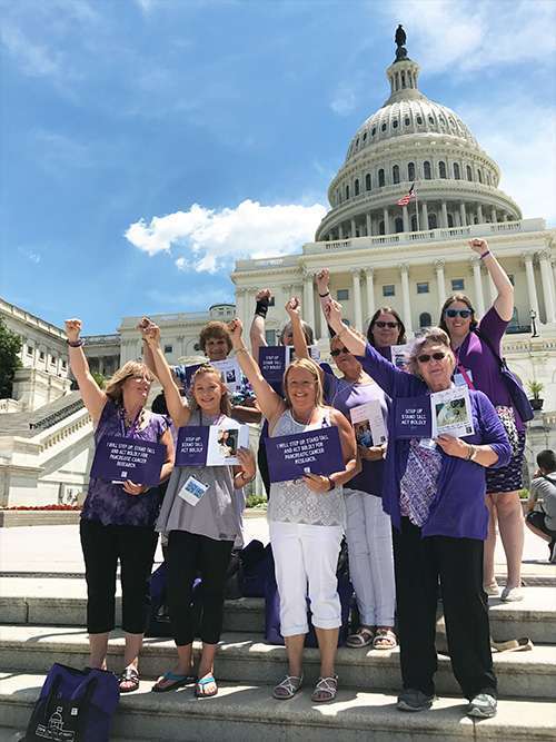 Pancreatic cancer advocates from Iowa raise their arms together in solidarity on the steps of the U.S. Capitol