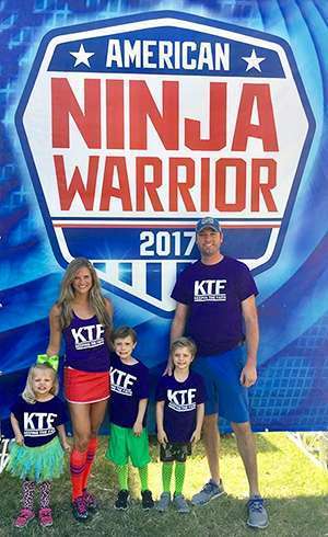 Brandi Monteverde with her three young children and husband on the set of American Ninja Warrior wearing family team shirts