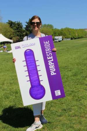 A PurpleStride participants holds a sign showing that PurpleStride Kansas City raised $335,000.