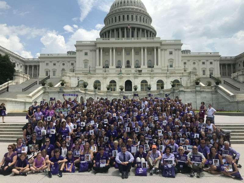 Over 100 pancreatic cancer survivors wearing purple gathered in front of Capitol Hill.
