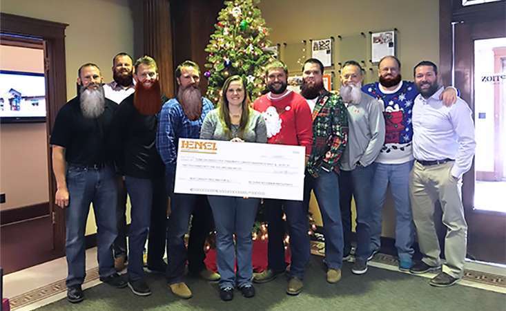 Fundraiser holds big novelty check with coworkers in support of fighting pancreatic cancer