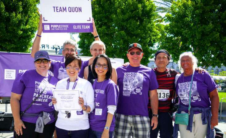 16-year pancreatic cancer survivor with team members of 5K walk event smile as top fundraisers