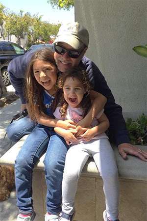 Pancreatic cancer survivor and father laughing with his two young daughters