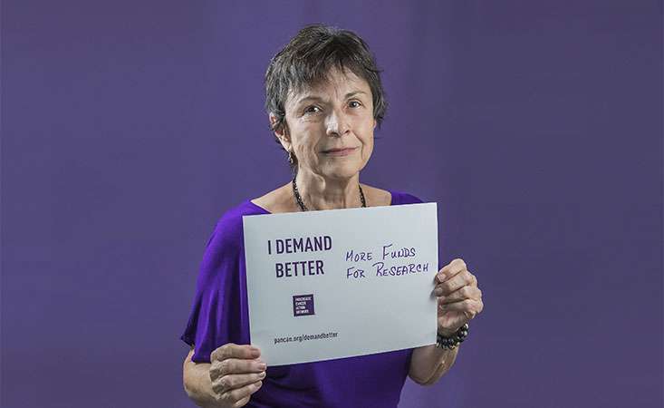 Survivor holds a sign saying she supports more pancreatic cancer research funding.