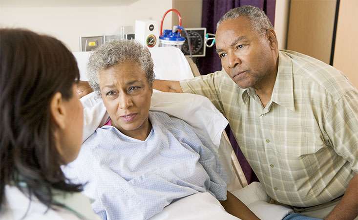 Pancreatic cancer patient supported by her caregiver speak with their doctor at the hospital