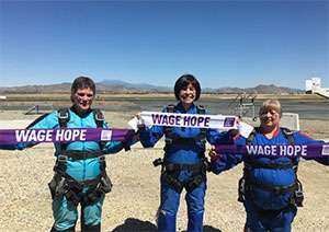 Three pancreatic cancer survivors hold Wage Hope banners before skydiving for the cause Marathon photo: Pancreatic cancer survivor holding medals from her Marathon runs