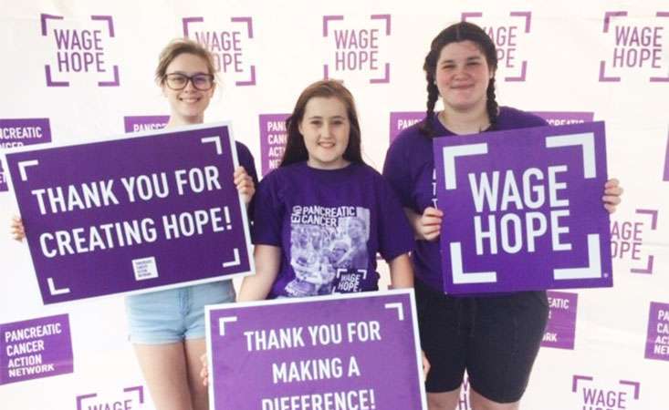 High schooler and her two friends holding signs of hope at the walk to end pancreatic cancer