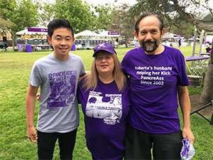 Teenage fundraiser stands with pancreatic cancer survivor and her husband at PurpleStride walk