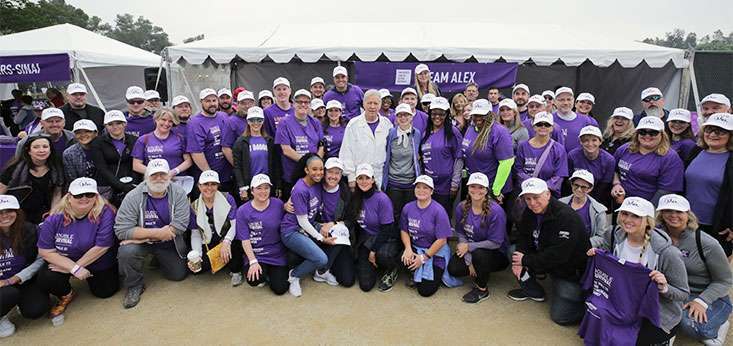 A team of “Jeopardy!” staff, crew, family and friends surrounds Alex Trebek.