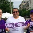Pancreatic cancer survivor holds “Wage Hope” banner with his wife and daughter at PurpleStride