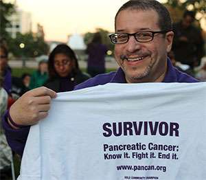 5-year pancreatic cancer survivor holds “Survivor” T-shirt at the walk to end pancreatic cancer