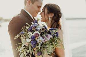 Bride and groom with bridal bouquet with purple flowers for pancreatic cancer awareness