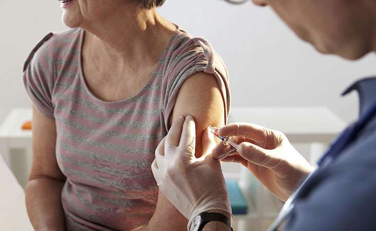 A pancreatic cancer caregiver gets flu shot from doctor