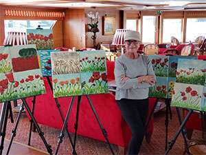 Stage 4 pancreatic cancer survivor with paintings on river cruise where she teaches