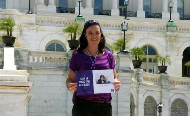 Advocacy Day volunteer at U.S. Capitol with photo of parents who died from pancreatic cancer