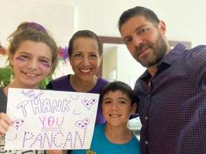 Pancreatic cancer survivor with her husband and children holding, 