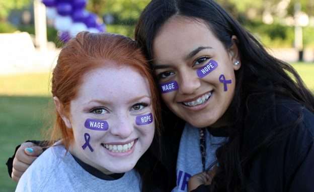 Two women attend PanCAN’s PurpleStride with stickers on their face.