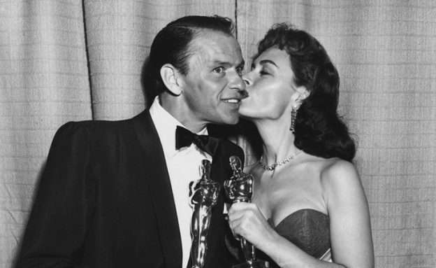Black and white photo of Donna Reed and Frank Sinatra with their Oscars