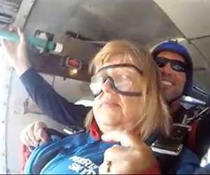Middle-aged Caucasian female getting ready to skydive from plane with 30s Caucasian male behind her