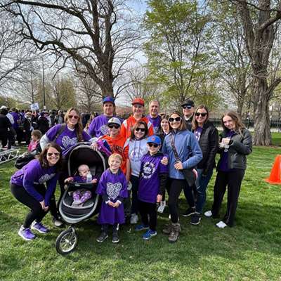 Sixteen people, including a baby in a stroller wear purple T-shirts at PanCAN PurpleStride.