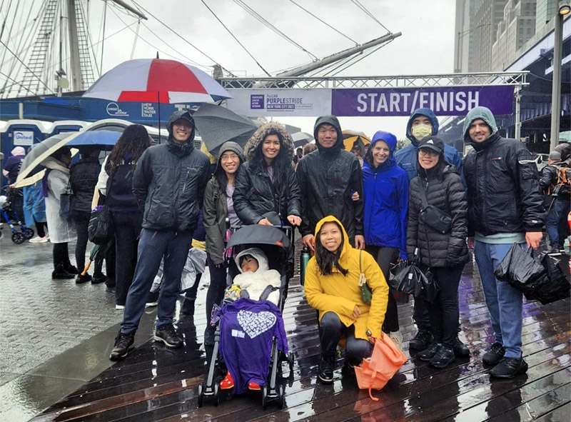 Nine people and a child in a stroller pose for a picture at PanCAN PurpleStride New York City.