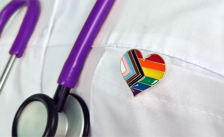close up of doctor wearing LGBTQ+ pride pin and stethoscope