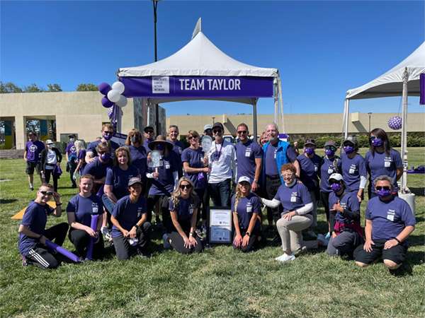 A group of nearly 25 members of Team Taylor pose for a group picture wearing purple at PanCAN PurpleStride Silicon Valley 2023.