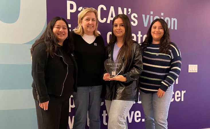 PanCAN staff member Abigail Dominguez, Lisa Kulok, 2024 awardee Karina Gutierrez, and last year’s awardee Brianne Flores all standing together posing for the picture in front of a purple wall with writing on it.
