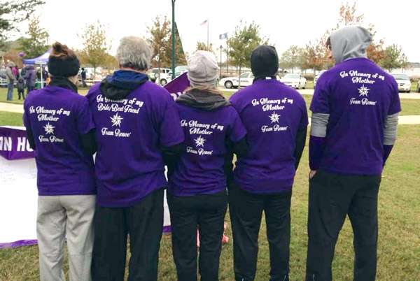 The backs of five people all wearing a purple shirt that says In Memory of my Mother Team Renee at a PanCAN PurpleStride event outside.