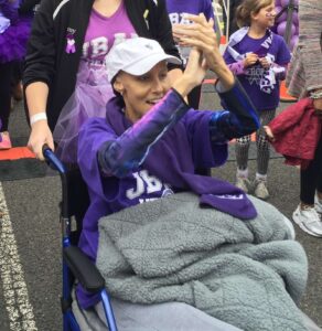 A woman in a wheelchair participating at a PanCAN PurpleStride charity walk.