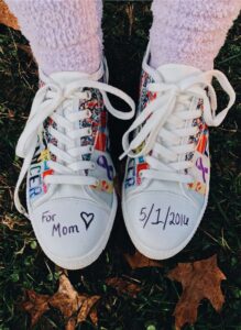 Tennis shoes decorated to support pancreatic cancer with the words FOR MOM on the toe of the shoe on the left and 5/1/2016 on the toe of the show on the right.