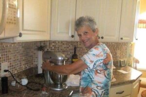Woman in her kitchen with a mixer baking.
